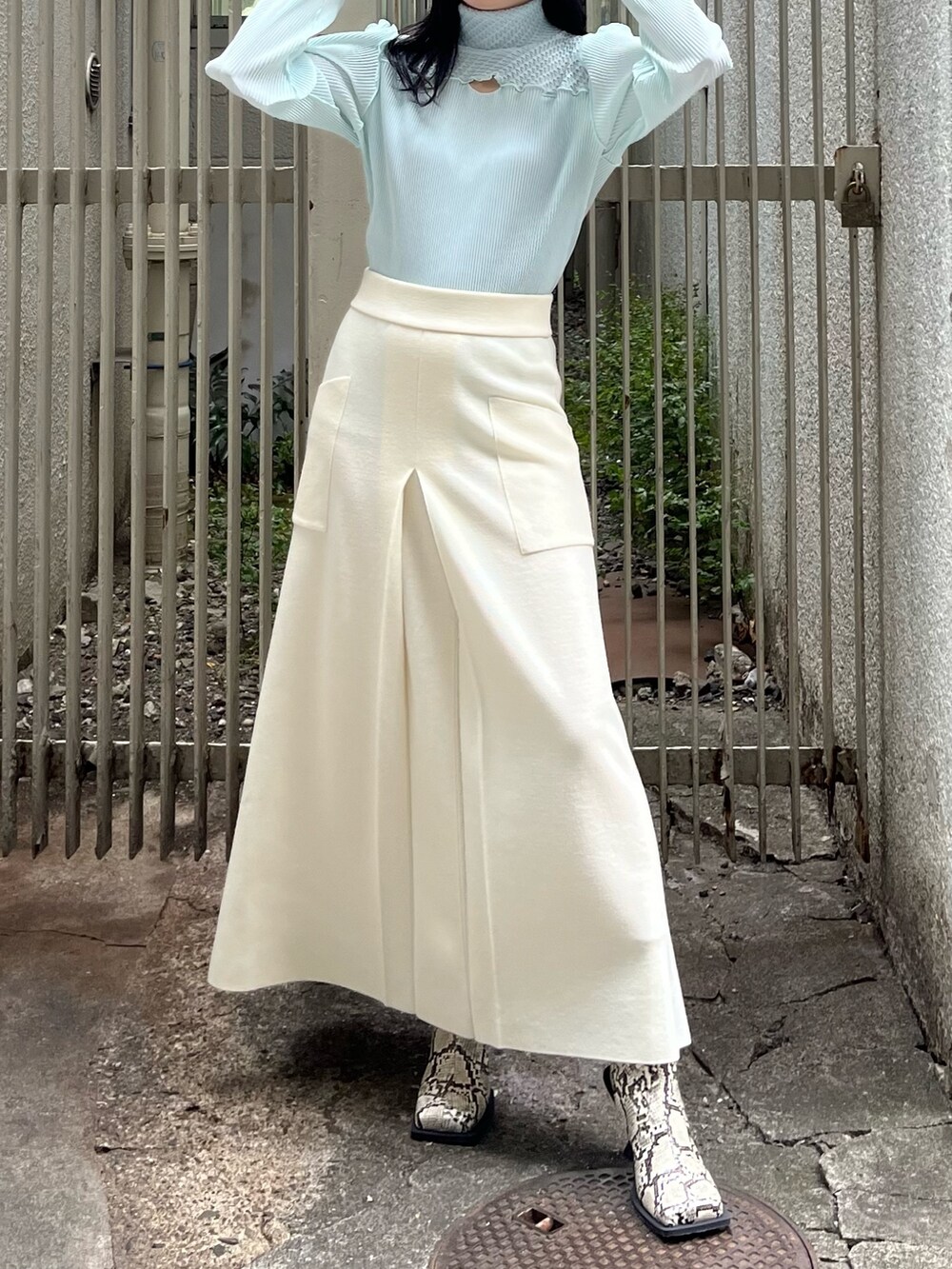 ブルー系のTシャツ/カットソー、ベージュ系のスカート、その他のブーツを着用したレディースの冬コーディネートの2枚目の写真
