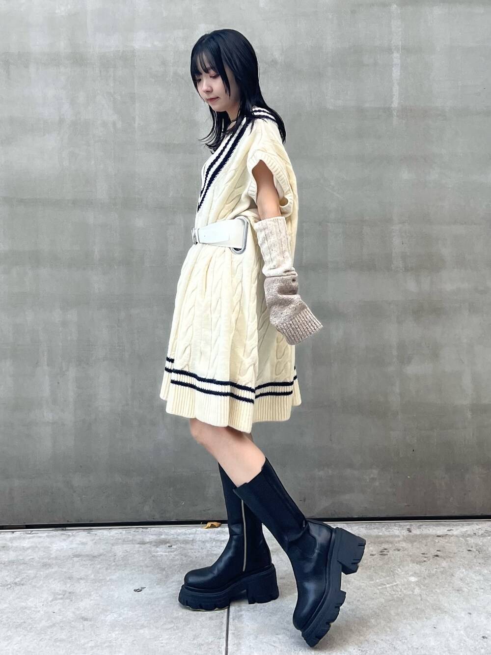 ブラック系のスカート、ブラック系のブーツ、ベージュ系のアームカバーを着用したレディースの秋コーディネートの3枚目の写真