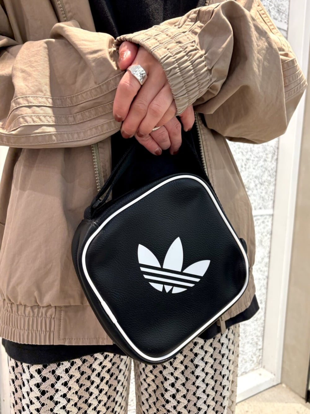 ブラウン系のナイロンジャケット、ブラック系のショルダーバッグ、ホワイト系のスウェットパンツを着用したレディースの春コーディネートの5枚目の写真