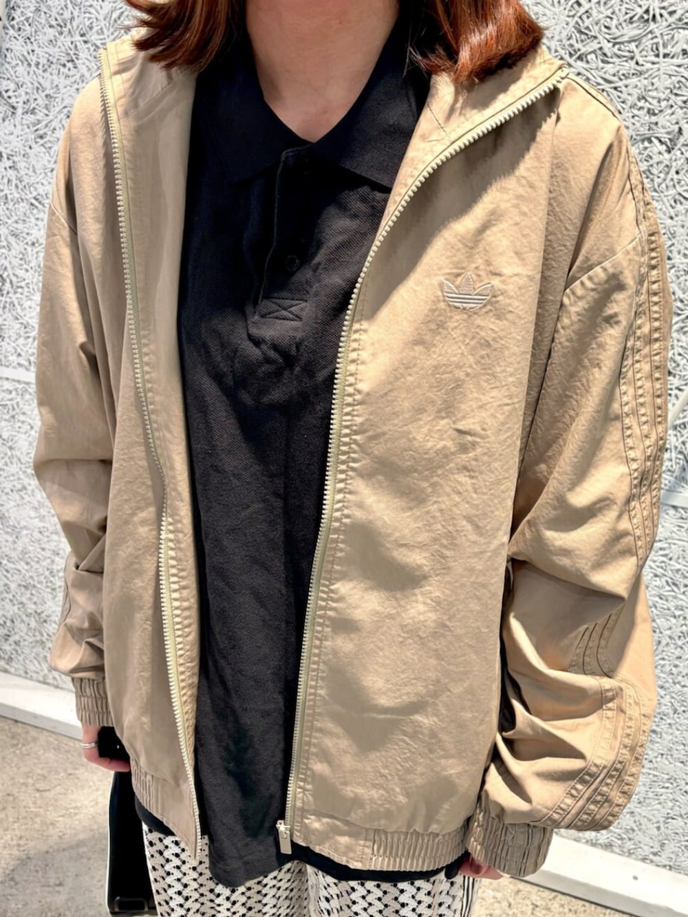 ブラウン系のナイロンジャケット、ブラック系のショルダーバッグ、ホワイト系のスウェットパンツを着用したレディースの春コーディネートの3枚目の写真