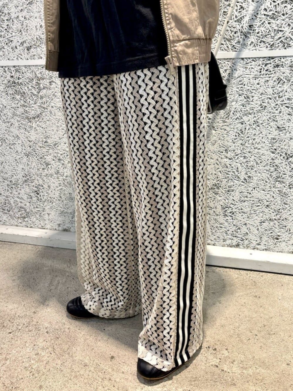 ブラウン系のナイロンジャケット、ブラック系のショルダーバッグ、ホワイト系のスウェットパンツを着用したレディースの春コーディネートの4枚目の写真