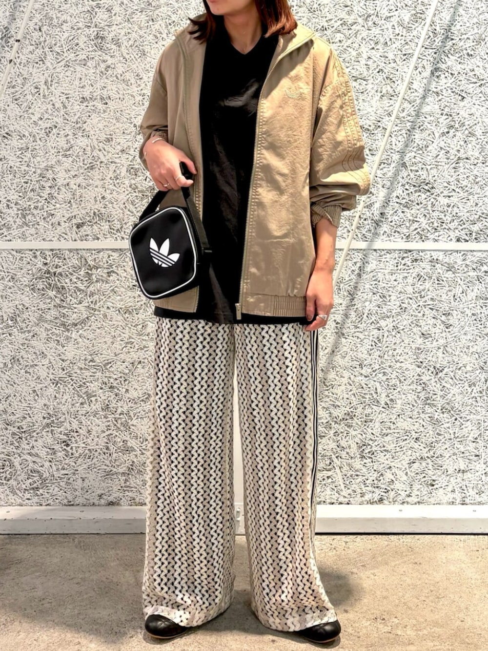 ブラウン系のナイロンジャケット、ブラック系のショルダーバッグ、ホワイト系のスウェットパンツを着用したレディースの春コーディネートの2枚目の写真