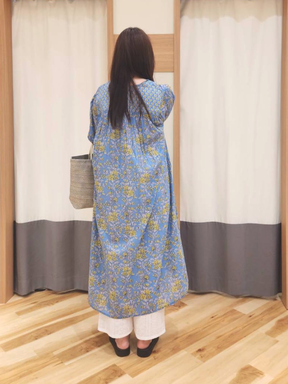 ブルー系のワンピース、ホワイト系のハンドバッグ、ブラック系のドレスシューズを着用したレディースの春コーディネートの2枚目の写真