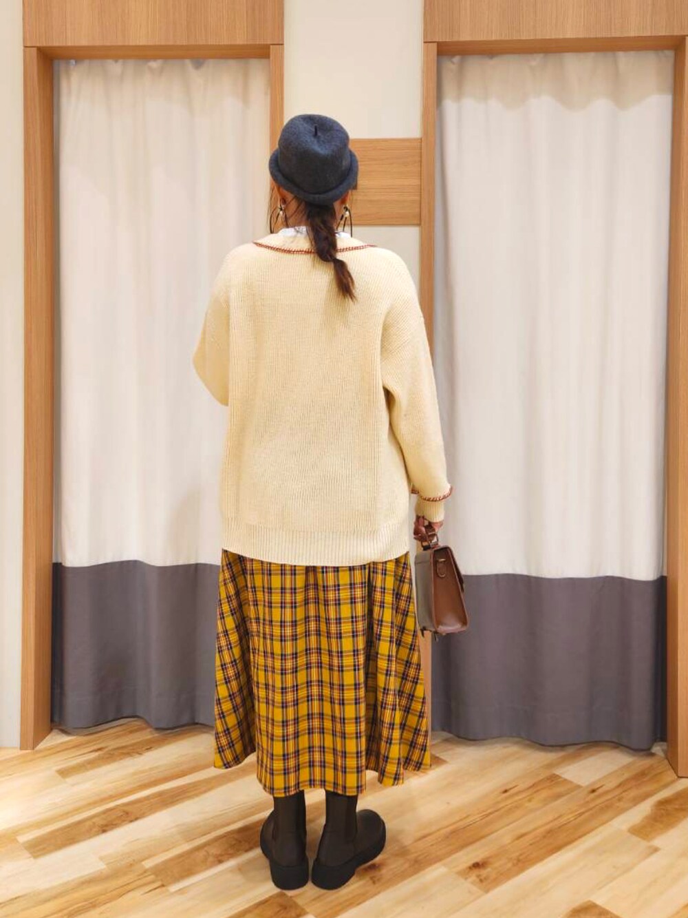 イエロー系のスカート、ブラック系のハンドバッグ、ブラック系のブーツを着用したレディースの冬コーディネートの2枚目の写真