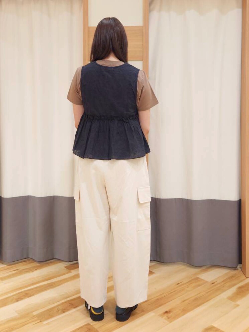 ブラック系のドレスシューズ、ホワイト系のハンドバッグ、ブラック系のベストを着用したレディースの春コーディネートの2枚目の写真