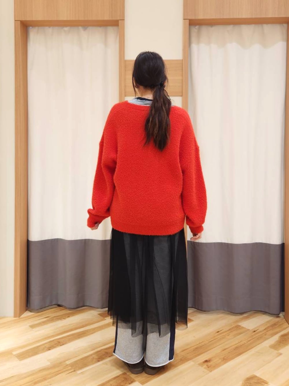 レッド系のニット/セーター、ブラック系のワンピース、グレー系のその他パンツを着用したレディースの冬コーディネートの2枚目の写真