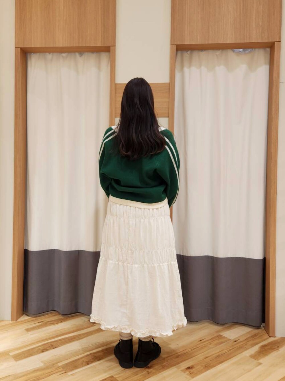 ブルー系のハンドバッグ、ホワイト系のスカート、グリーン系のカーディガン/ボレロを着用したレディースの冬コーディネートの2枚目の写真