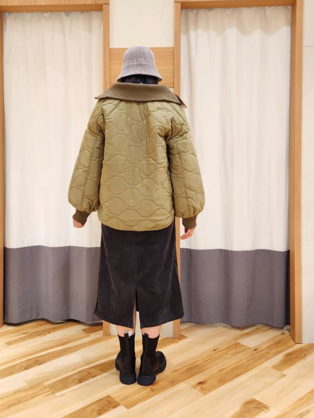 グリーン系のノーカラージャケット、グレー系のワンピース、ブラック系のブーツを着用したレディースの秋コーディネートの2枚目の写真