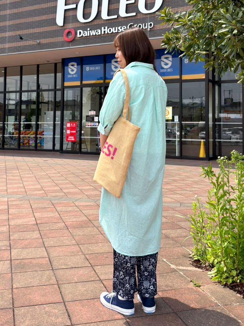 グリーン系のワンピース、ホワイト系のTシャツ/カットソー、ブラウン系のハンドバッグを着用したレディースの春コーディネートの2枚目の写真