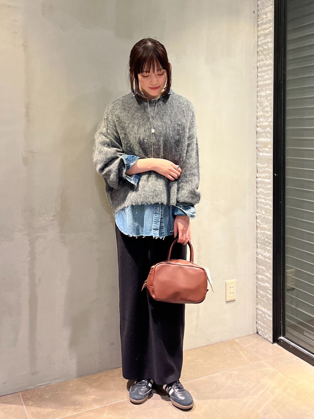 ブルー系のシャツ/ブラウス、ブラック系のスカート、グレー系のニット/セーターを着用したレディースの冬コーディネートの4枚目の写真