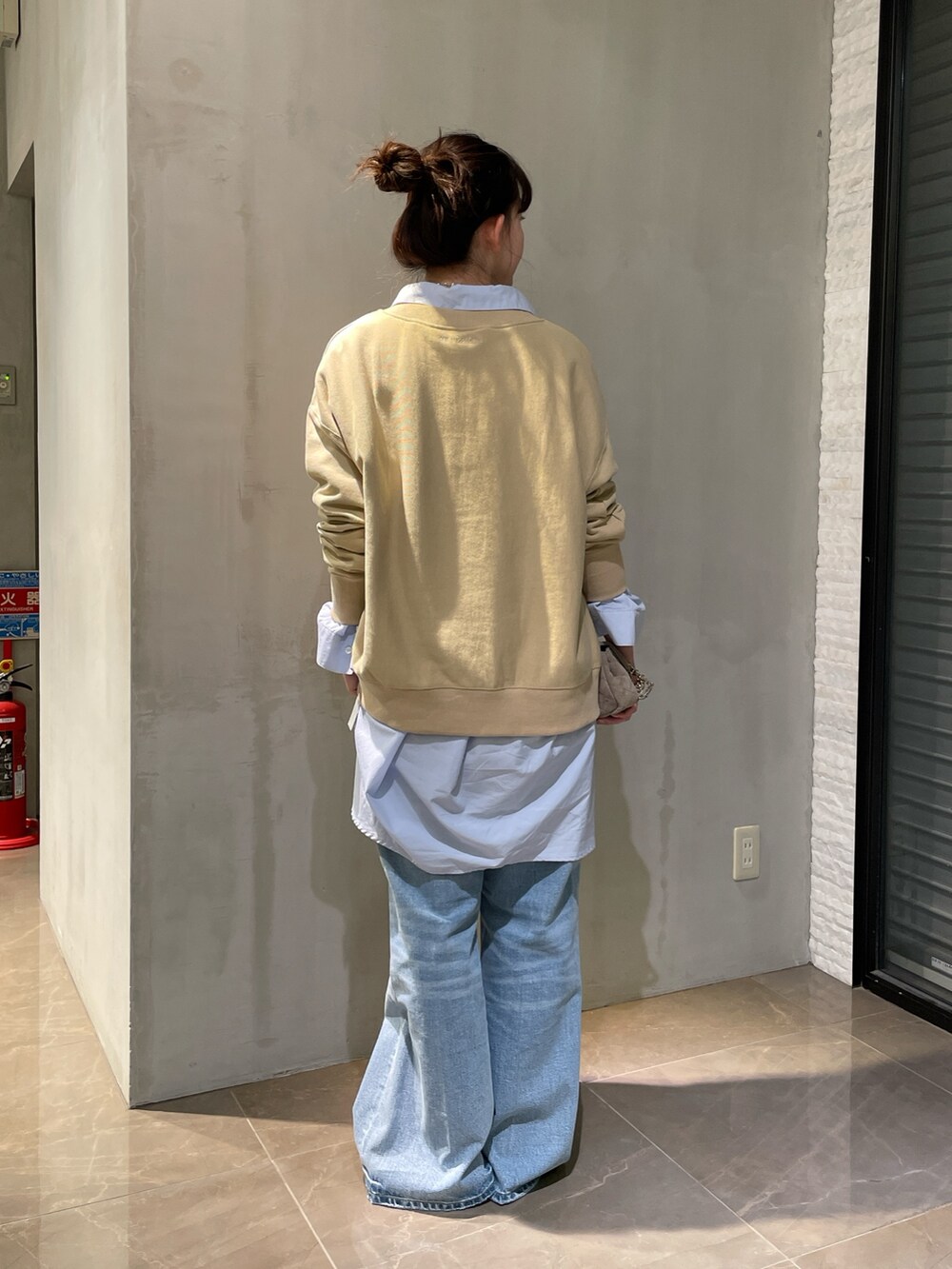 ベージュ系のスウェット、ブルー系のシャツ/ブラウス、ブルー系のデニムパンツを着用したレディースの冬コーディネートの2枚目の写真