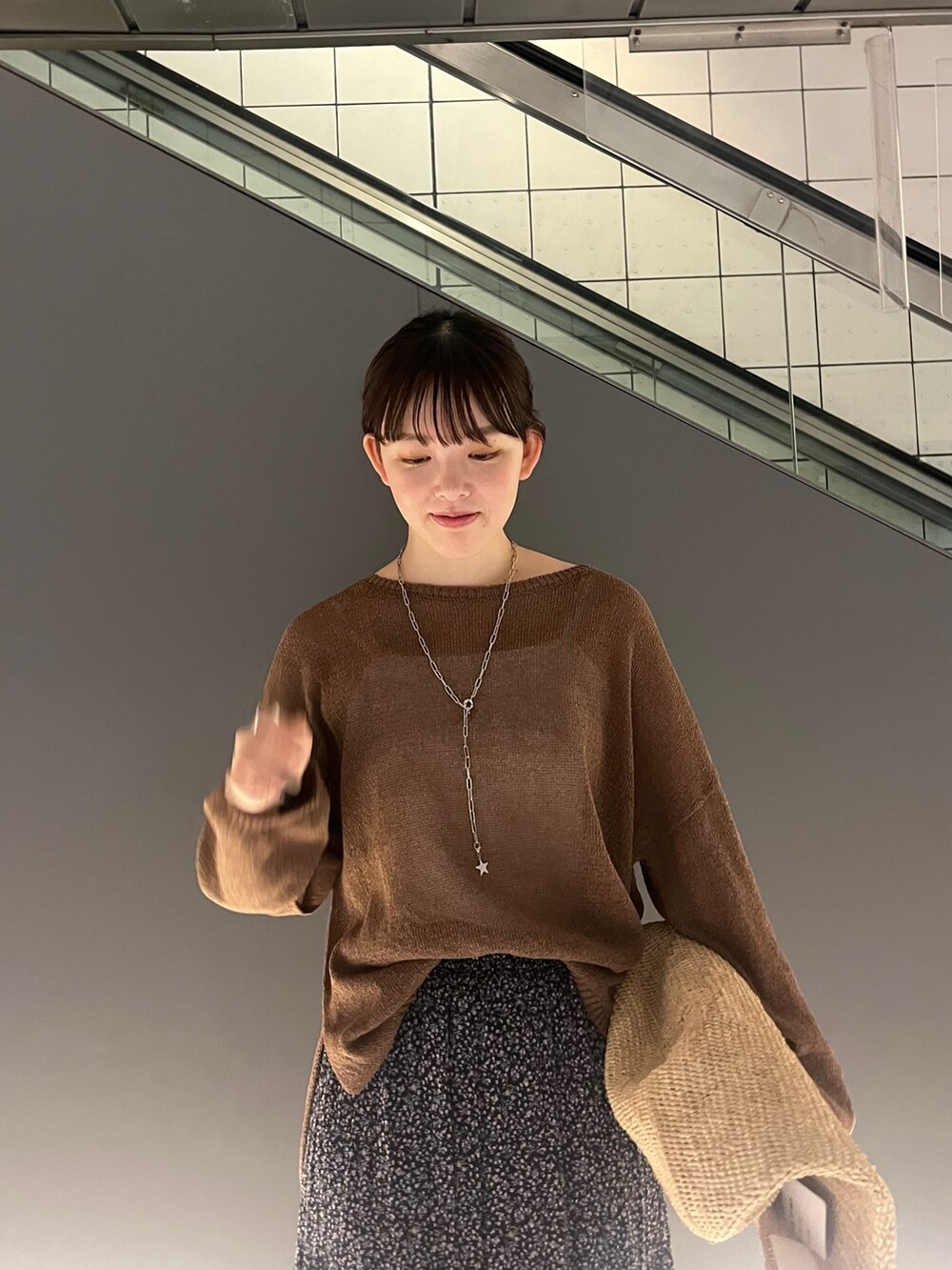 ブラウン系のニット/セーター、ピンク系のスカート、ベージュ系のかごバッグを着用したレディースの夏コーディネートの2枚目の写真