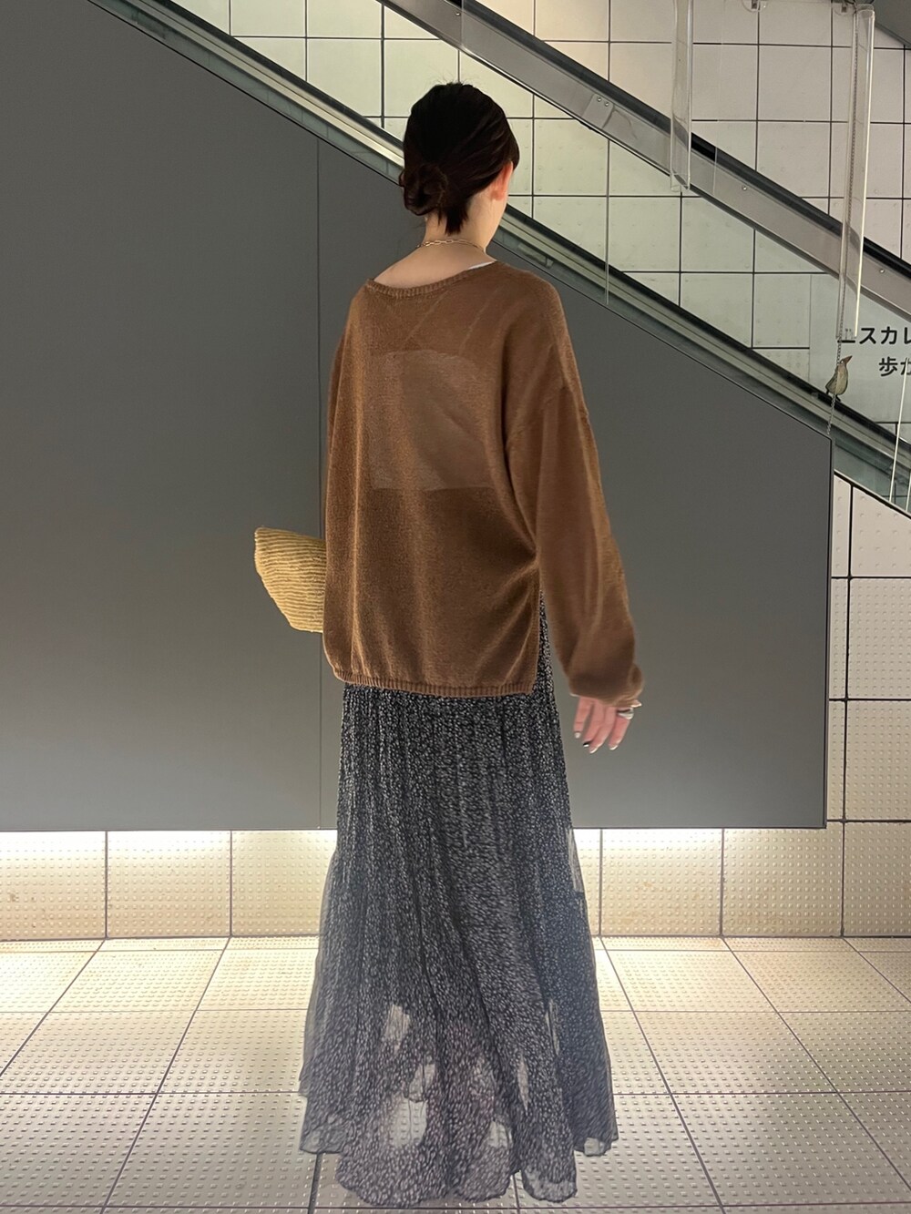 ブラウン系のニット/セーター、ピンク系のスカート、ベージュ系のかごバッグを着用したレディースの夏コーディネートの3枚目の写真