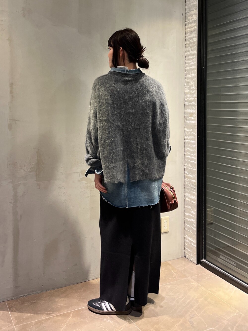 ブルー系のシャツ/ブラウス、ブラック系のスカート、グレー系のニット/セーターを着用したレディースの冬コーディネートの3枚目の写真