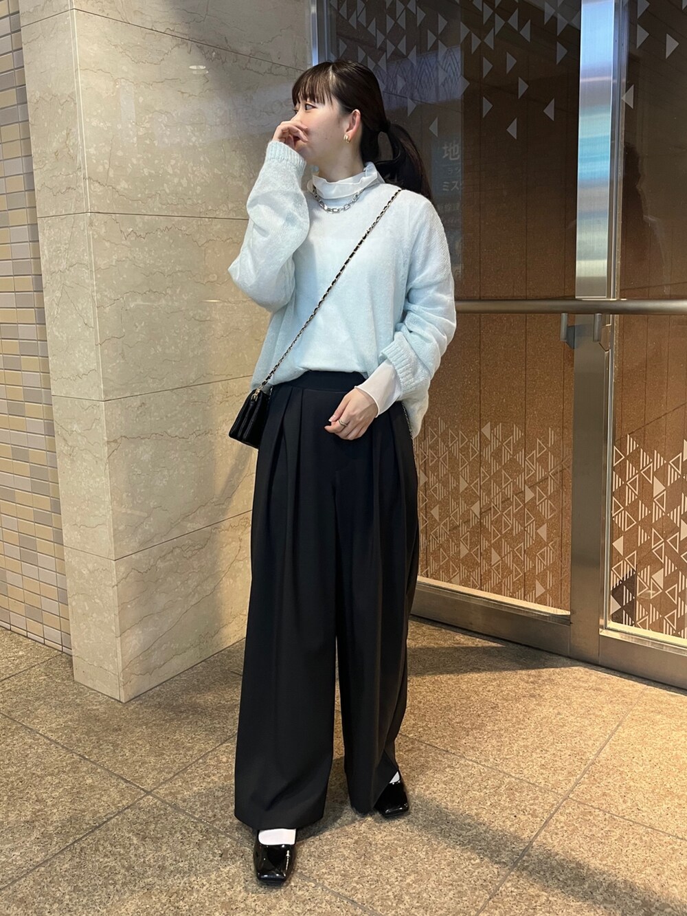 ブラック系のスラックス、ブラック系のショルダーバッグ、ホワイト系のTシャツ/カットソーを着用したレディースの秋コーディネートの4枚目の写真