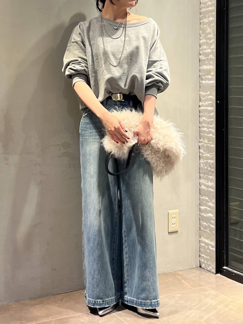 シルバー系のパンプス、ホワイト系のショルダーバッグ、ブルー系のデニムパンツを着用したレディースの秋コーディネートの3枚目の写真