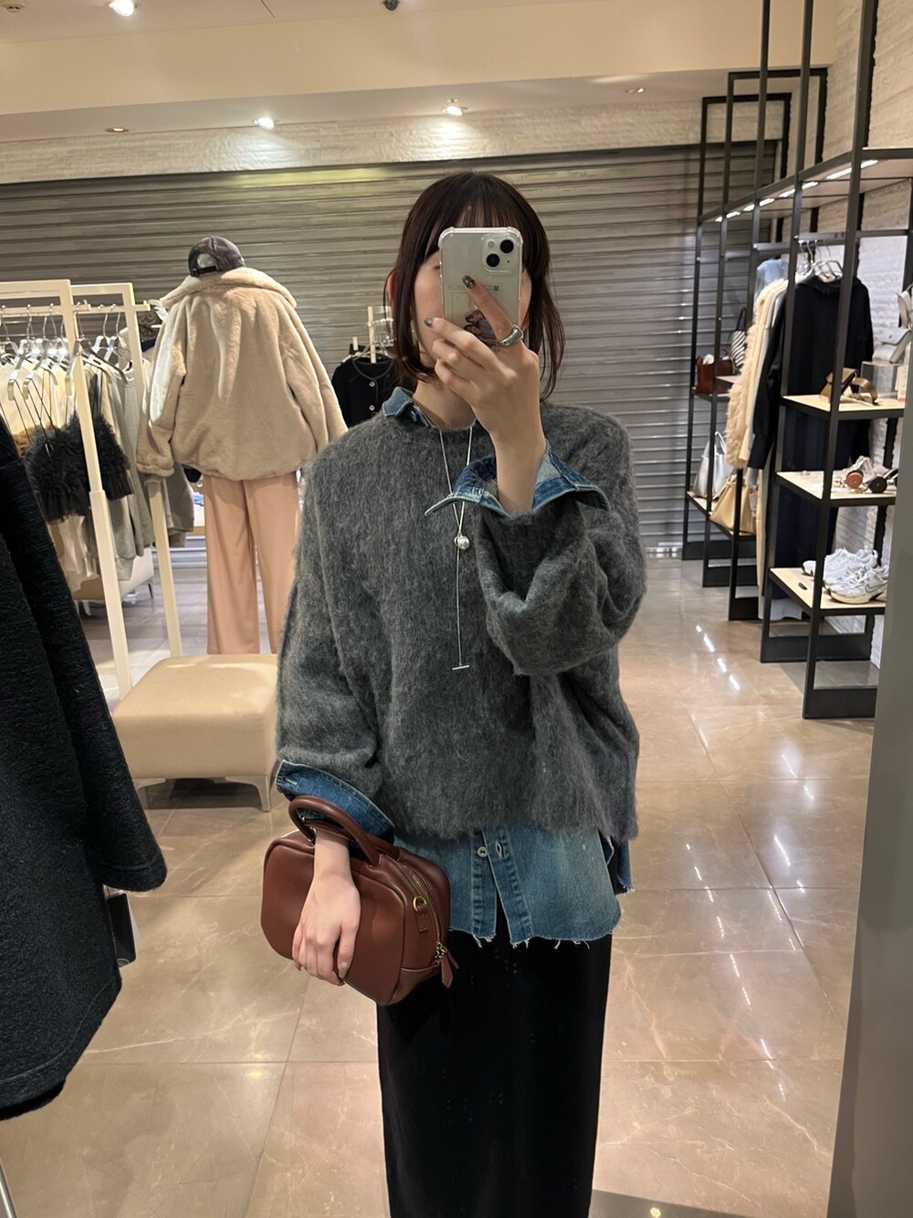 ブルー系のシャツ/ブラウス、ブラック系のスカート、グレー系のニット/セーターを着用したレディースの冬コーディネートの2枚目の写真