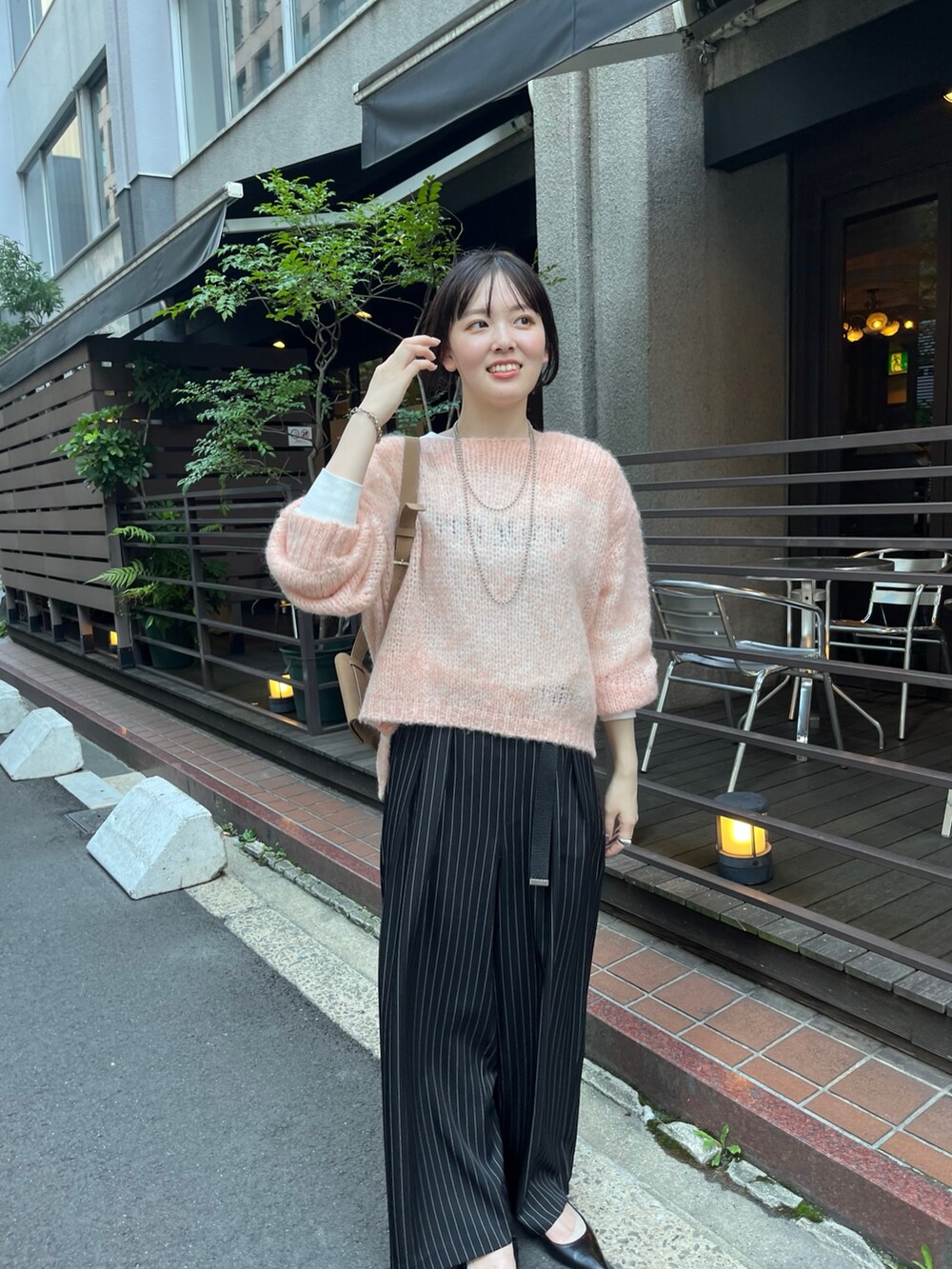 ピンク系のニット/セーター、ベージュ系のショルダーバッグ、ブルー系のその他パンツを着用したレディースの秋コーディネートの2枚目の写真