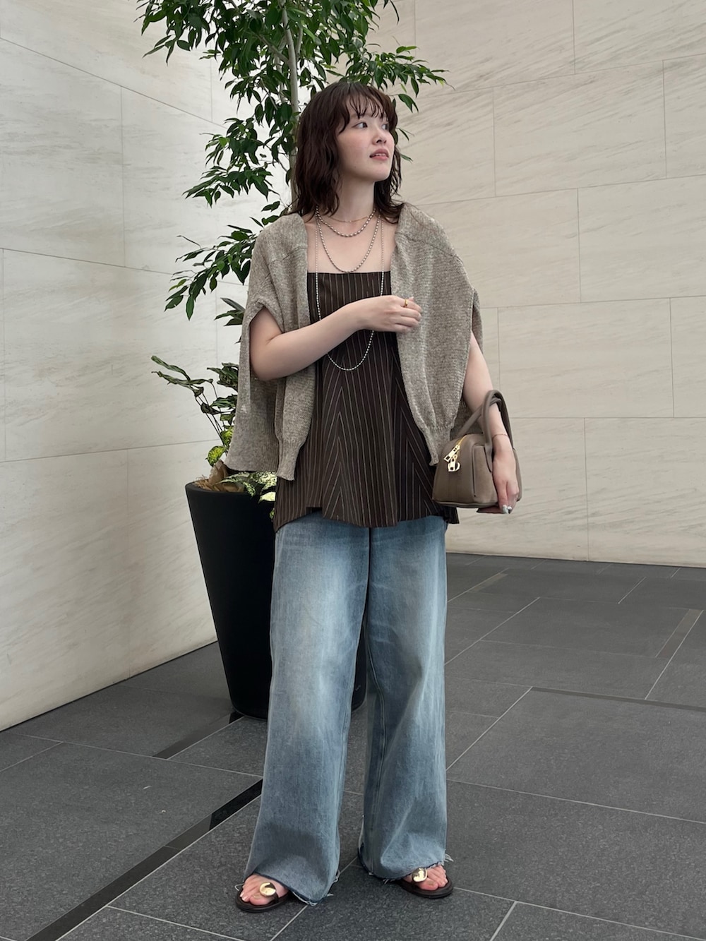 ブルー系のデニムパンツ、ブラウン系のキャミソール、ベージュ系のカーディガン/ボレロを着用したレディースの夏コーディネートの2枚目の写真