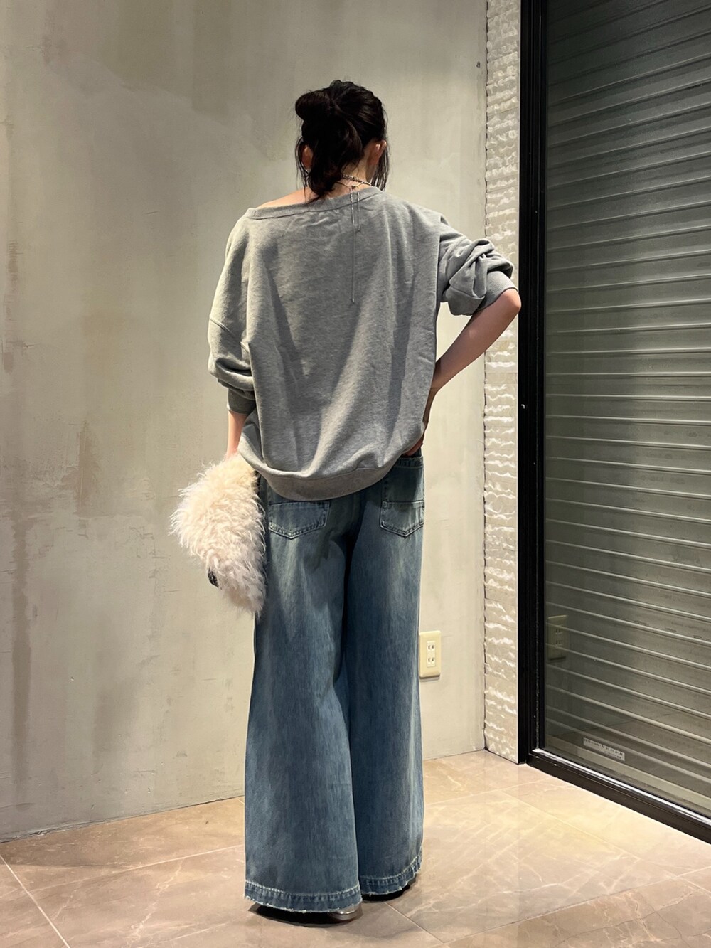 シルバー系のパンプス、ホワイト系のショルダーバッグ、ブルー系のデニムパンツを着用したレディースの秋コーディネートの5枚目の写真