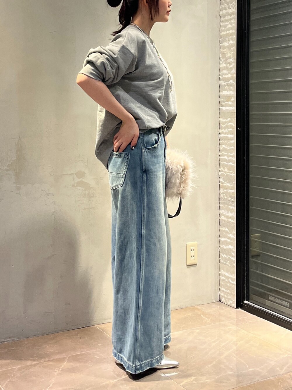 シルバー系のパンプス、ホワイト系のショルダーバッグ、ブルー系のデニムパンツを着用したレディースの秋コーディネートの4枚目の写真