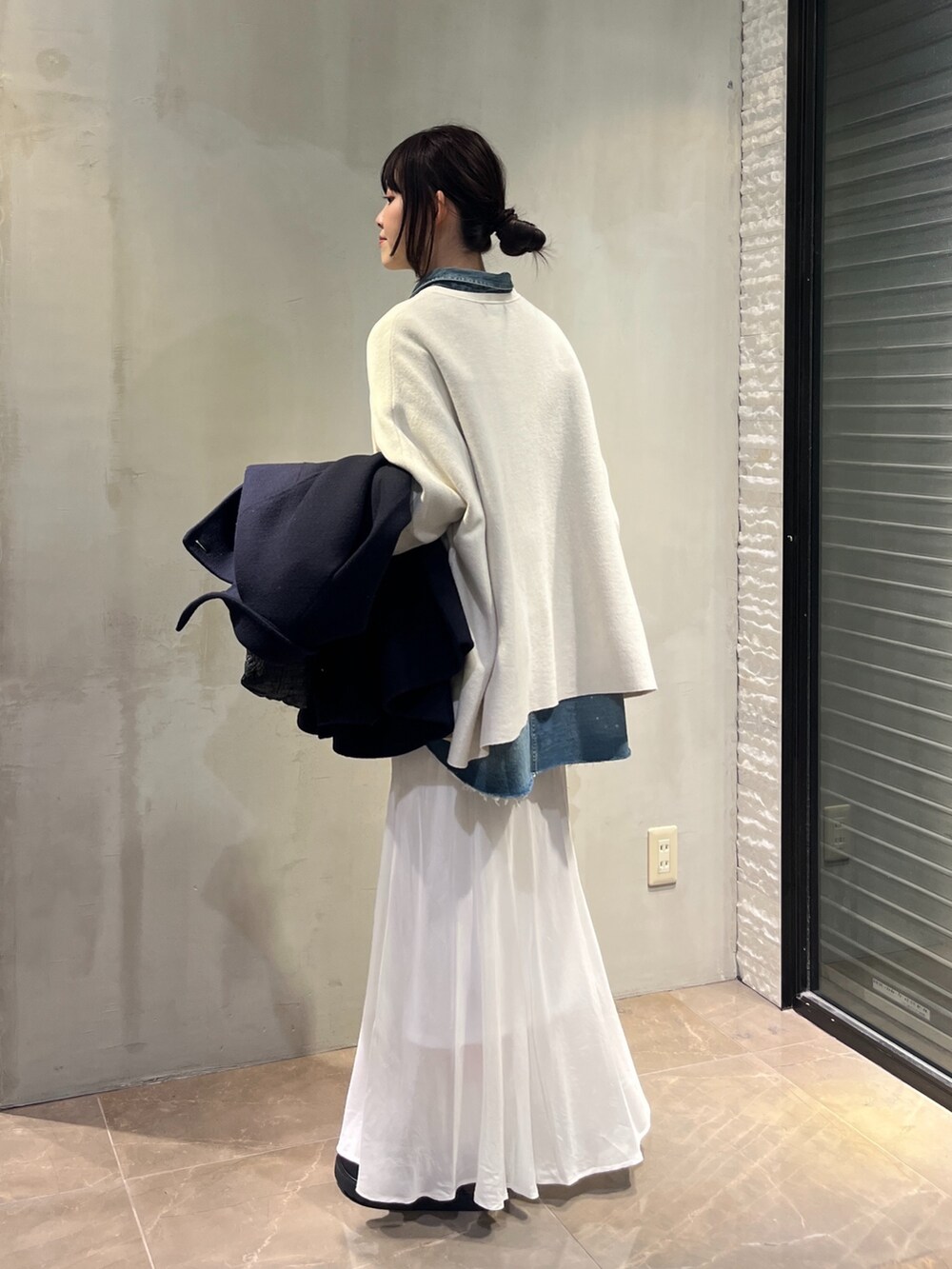 ホワイト系のスカート、ブルー系のシャツ/ブラウス、ホワイト系のニット/セーターを着用したレディースの冬コーディネートの2枚目の写真