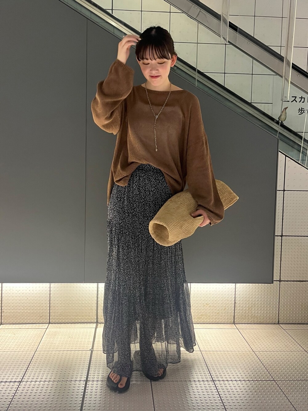 ブラウン系のニット/セーター、ピンク系のスカート、ベージュ系のかごバッグを着用したレディースの夏コーディネートの6枚目の写真