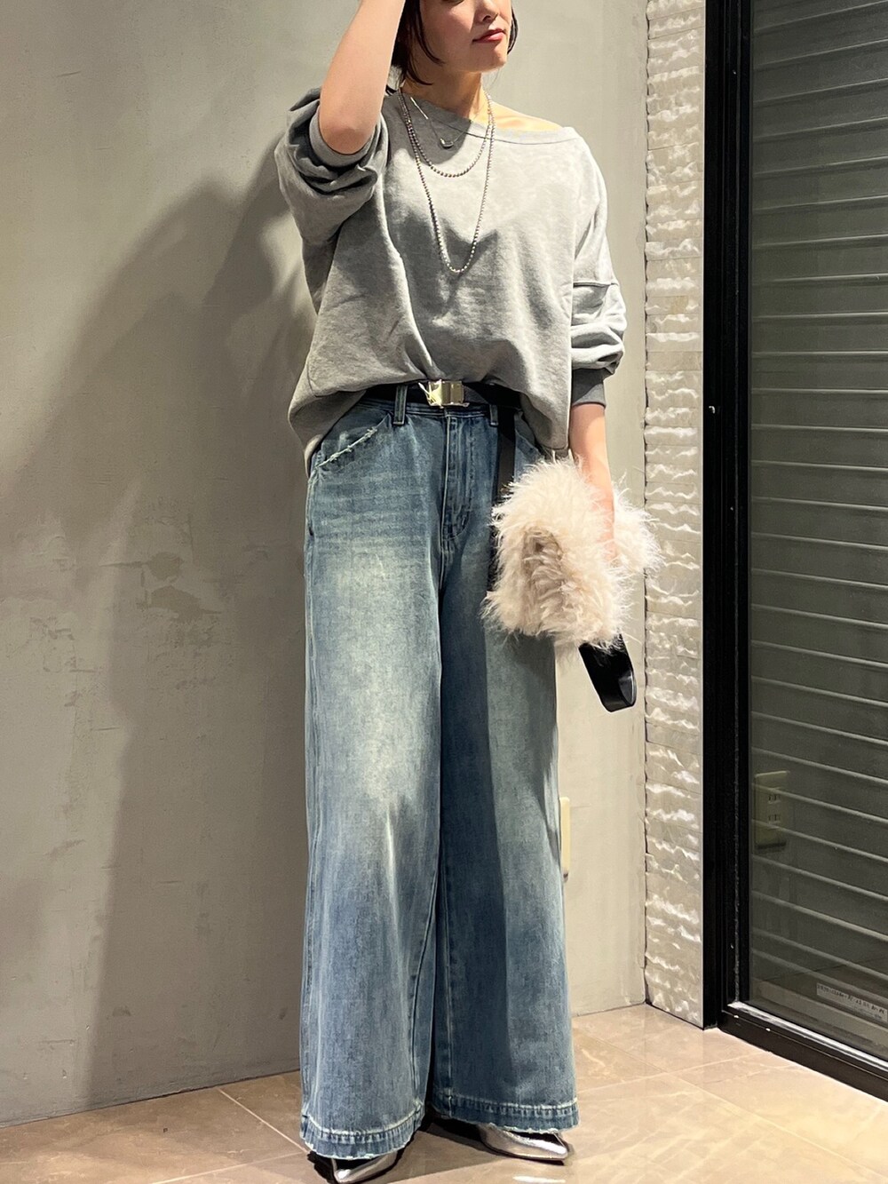 シルバー系のパンプス、ホワイト系のショルダーバッグ、ブルー系のデニムパンツを着用したレディースの秋コーディネートの6枚目の写真