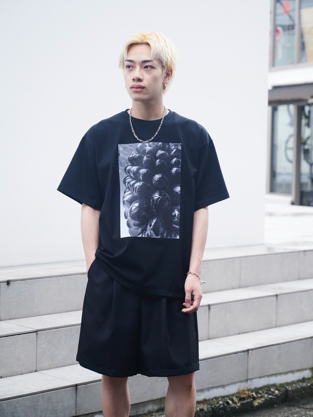 ホワイト系のTシャツ/カットソー、ブラック系のスラックス、ブラック系のサンダルを着用したメンズの夏コーディネートの4枚目の写真
