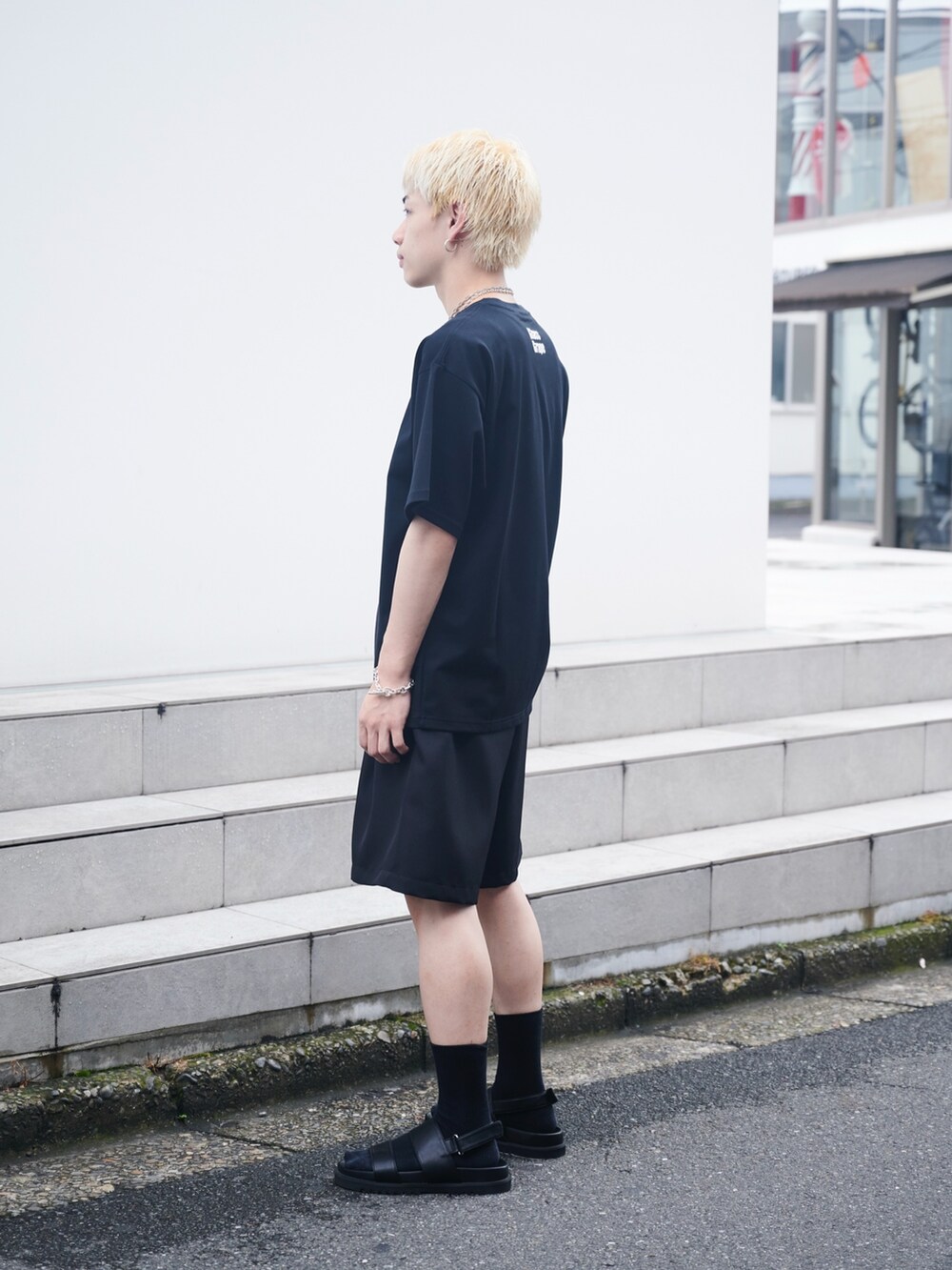 ホワイト系のTシャツ/カットソー、ブラック系のスラックス、ブラック系のサンダルを着用したメンズの夏コーディネートの2枚目の写真