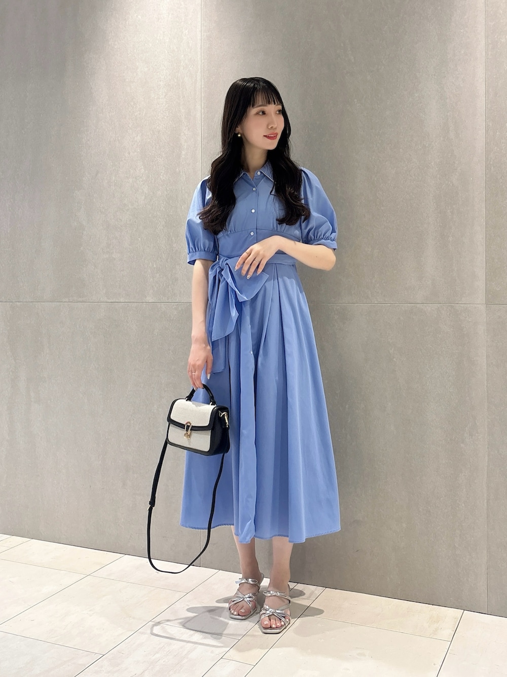 ブルー系のワンピース、ブラック系のショルダーバッグ、シルバー系のパンプスを着用したレディースの夏コーディネートの4枚目の写真