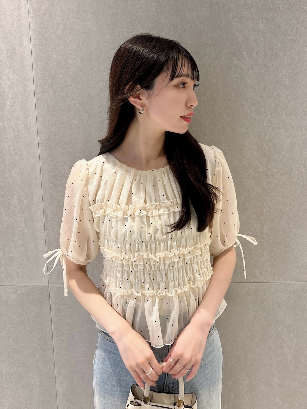 ホワイト系のシャツ/ブラウス、ホワイト系のショルダーバッグ、ブルー系のデニムパンツを着用したレディースの秋コーディネートの6枚目の写真