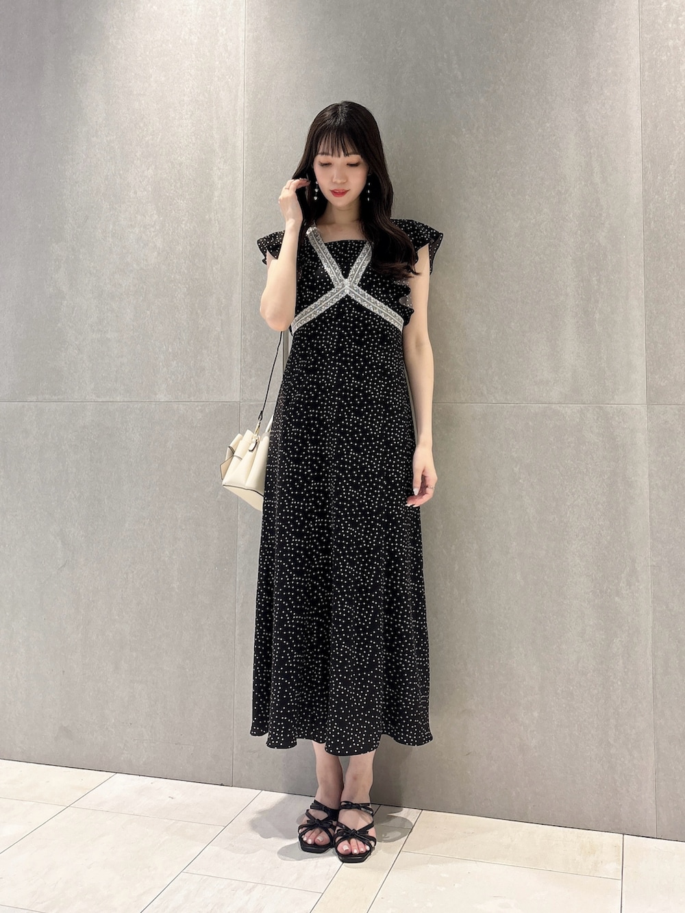 ブラック系のワンピース、ブラック系のパンプス、ホワイト系のショルダーバッグを着用したレディースの夏コーディネートの5枚目の写真