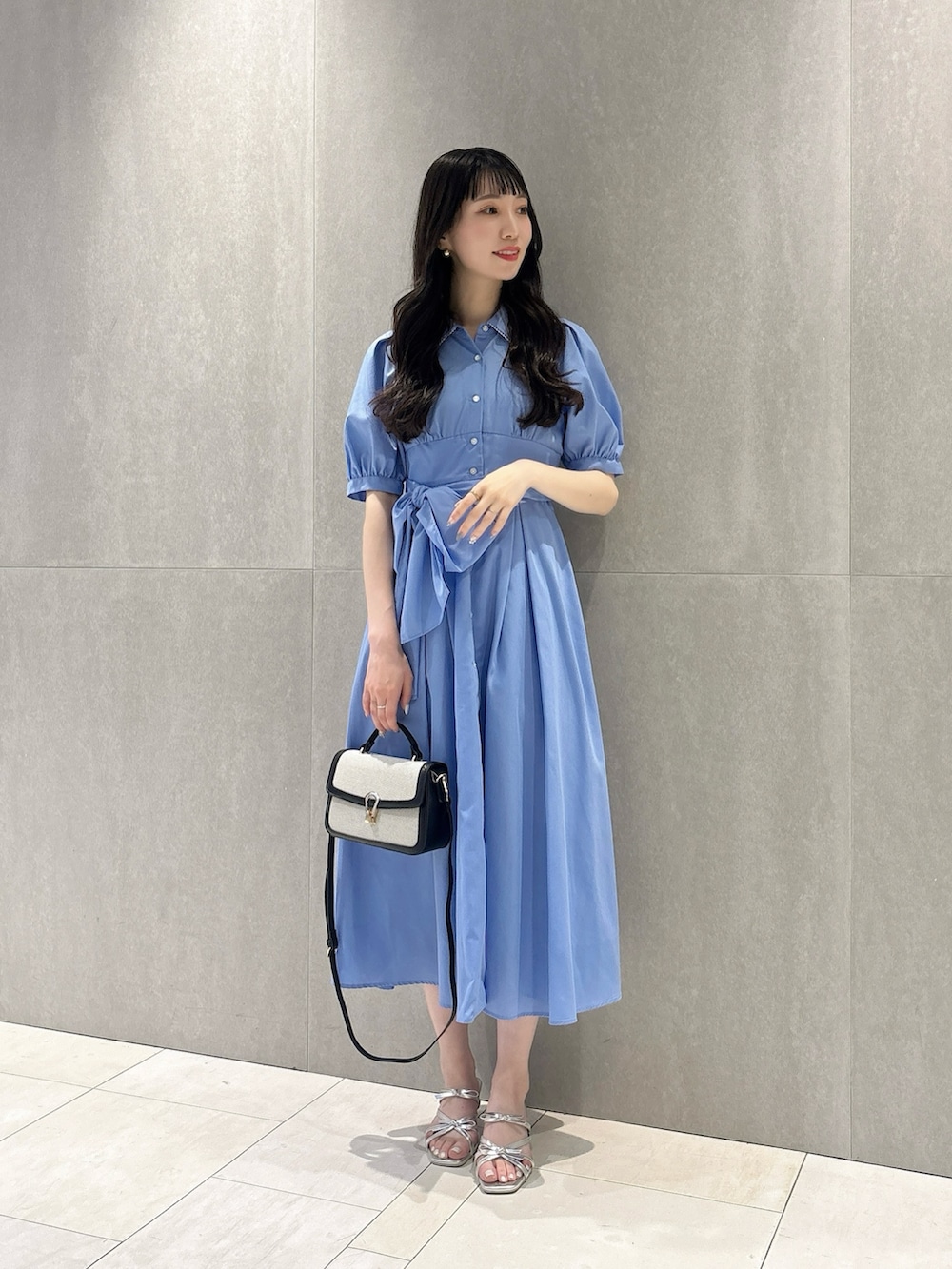 ブルー系のワンピース、ブラック系のショルダーバッグ、シルバー系のパンプスを着用したレディースの夏コーディネートの2枚目の写真