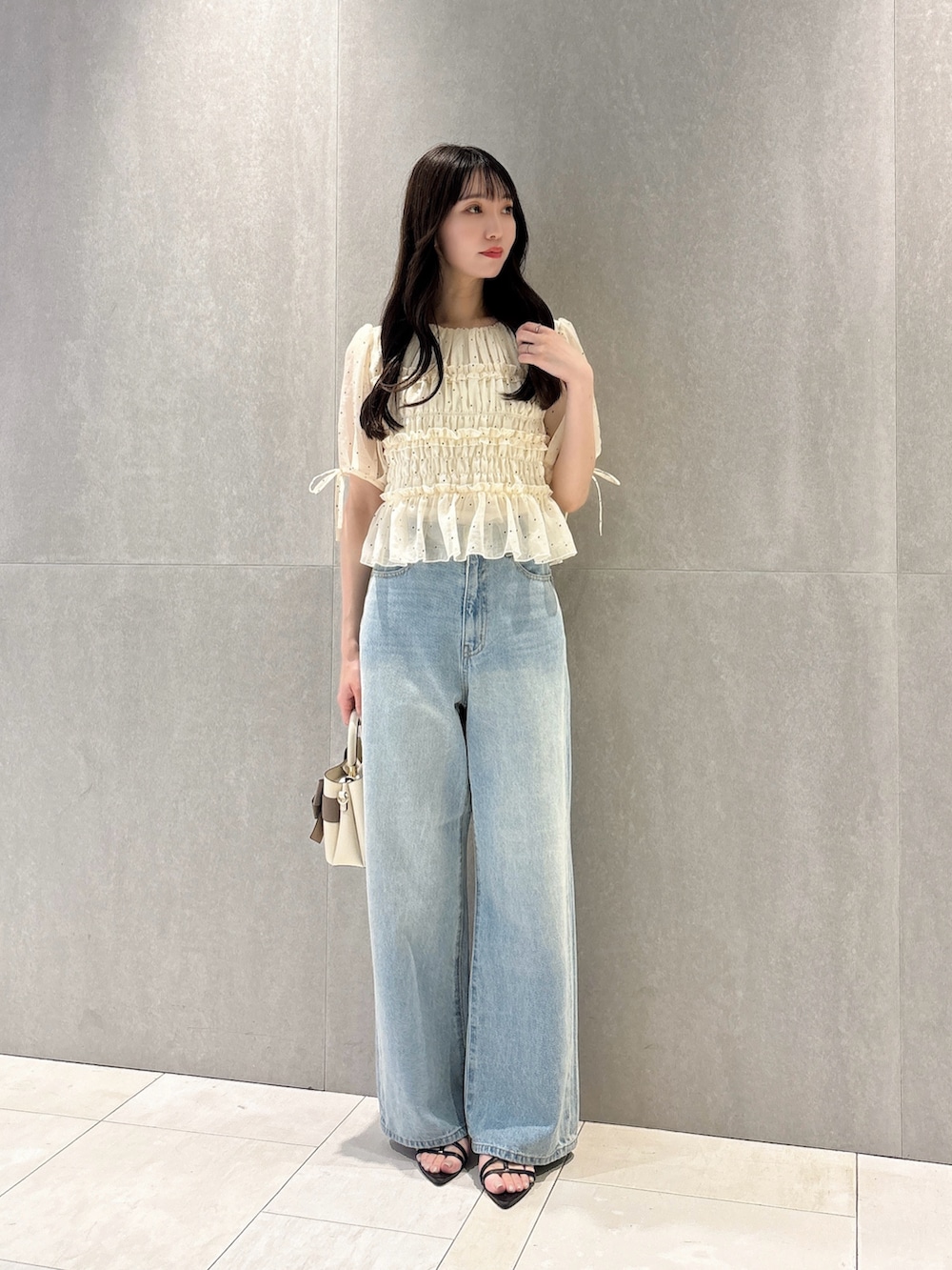 ホワイト系のシャツ/ブラウス、ホワイト系のショルダーバッグ、ブルー系のデニムパンツを着用したレディースの秋コーディネートの2枚目の写真