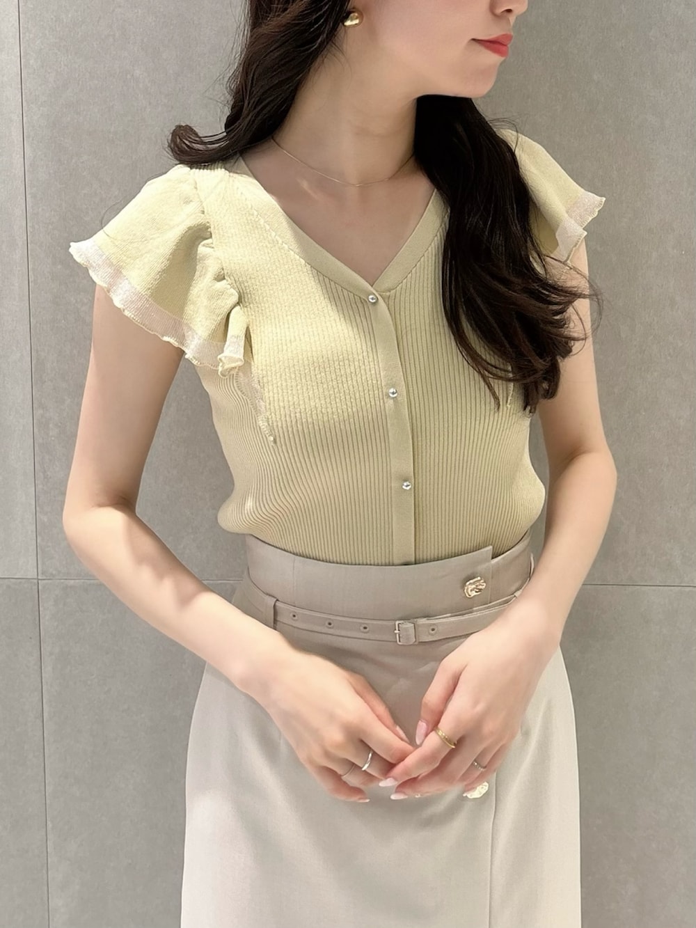 ベージュ系のスカート、イエロー系のニット/セーター、シルバー系のパンプスを着用したレディースの春コーディネートの7枚目の写真