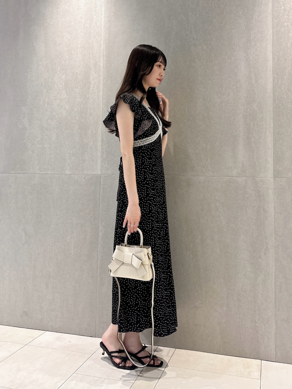 ブラック系のワンピース、ブラック系のパンプス、ホワイト系のショルダーバッグを着用したレディースの夏コーディネートの3枚目の写真