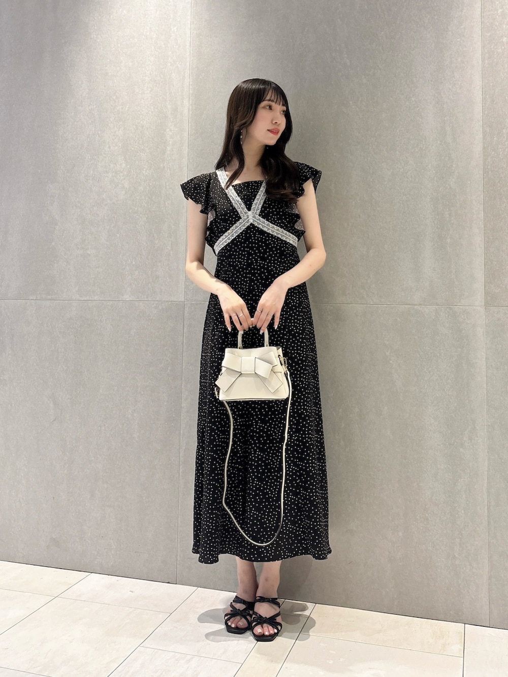 ブラック系のワンピース、ブラック系のパンプス、ホワイト系のショルダーバッグを着用したレディースの夏コーディネートの2枚目の写真
