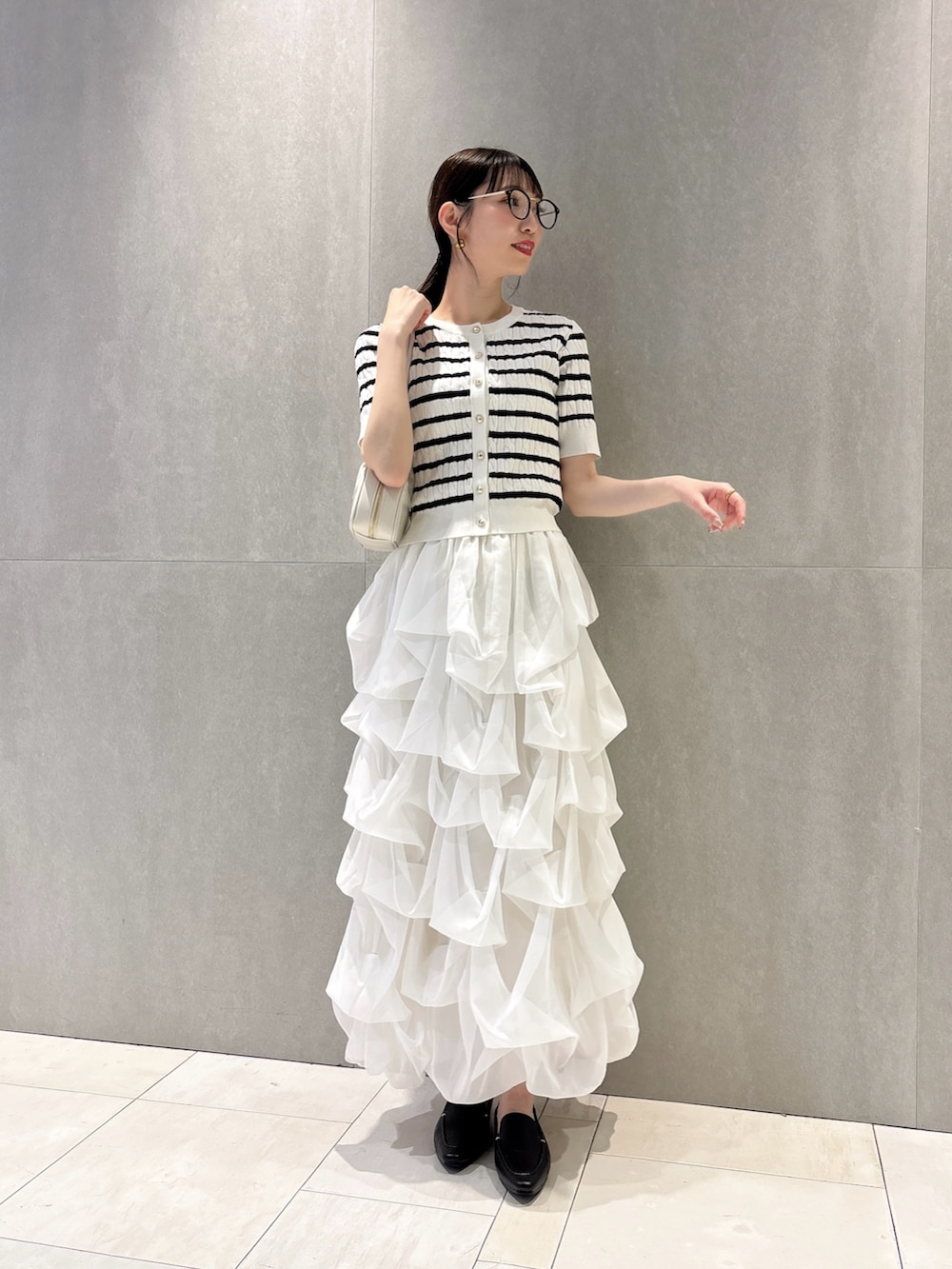 ホワイト系のカーディガン/ボレロ、ホワイト系のスカート、ホワイト系のショルダーバッグを着用したレディースの夏コーディネートの2枚目の写真