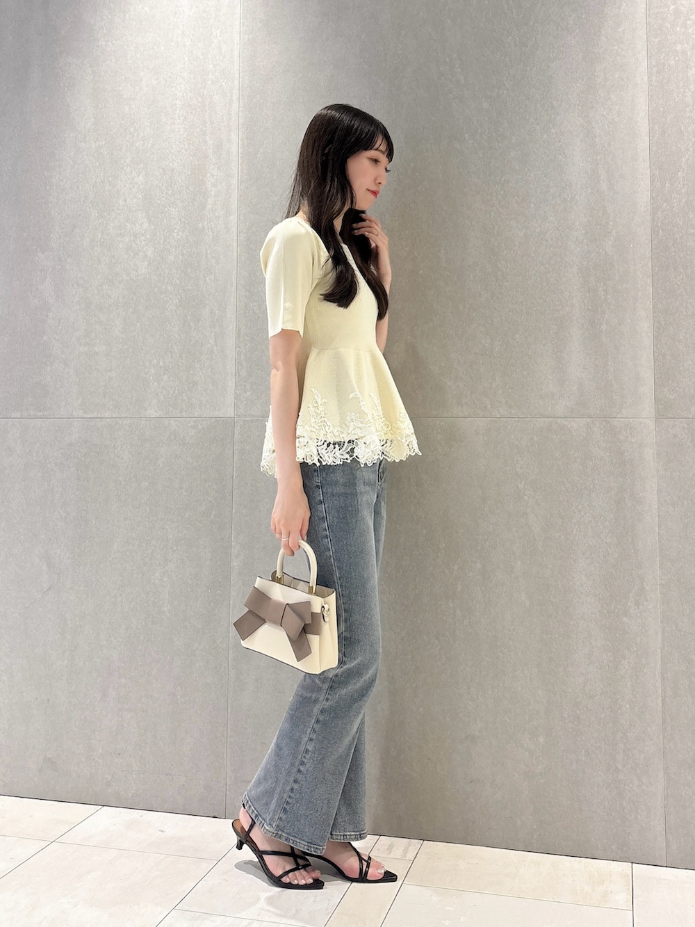 ホワイト系のニット/セーター、ブルー系のデニムパンツ、ホワイト系のショルダーバッグを着用したレディースの夏コーディネートの4枚目の写真