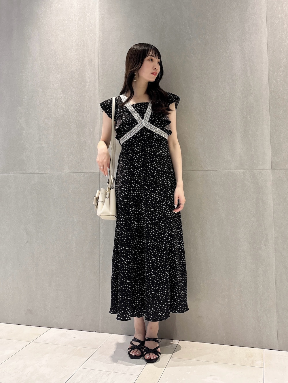 ブラック系のワンピース、ブラック系のパンプス、ホワイト系のショルダーバッグを着用したレディースの夏コーディネートの6枚目の写真