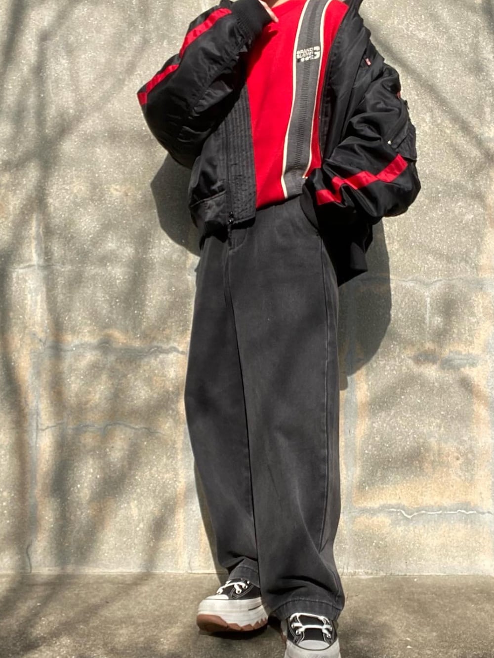 ブラック系のスニーカー、ブラック系のデニムパンツ、レッド系のニット/セーターを着用したメンズの冬コーディネートの2枚目の写真