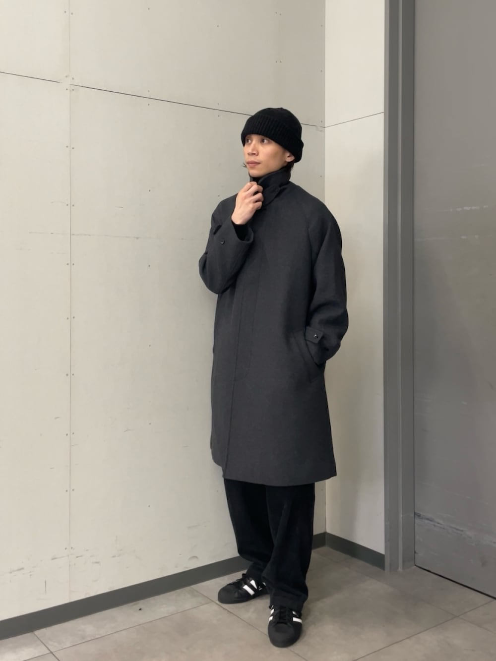 グレー系のステンカラーコート、ブラック系のニット/セーター、グレー系のその他パンツを着用したメンズの秋コーディネートの5枚目の写真