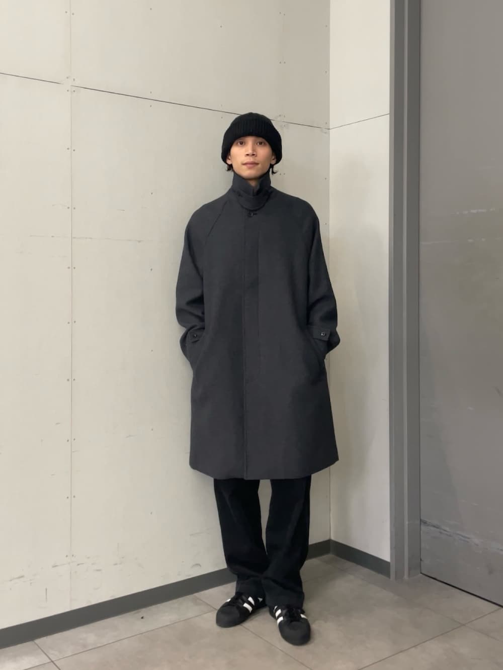 グレー系のステンカラーコート、ブラック系のニット/セーター、グレー系のその他パンツを着用したメンズの秋コーディネートの4枚目の写真