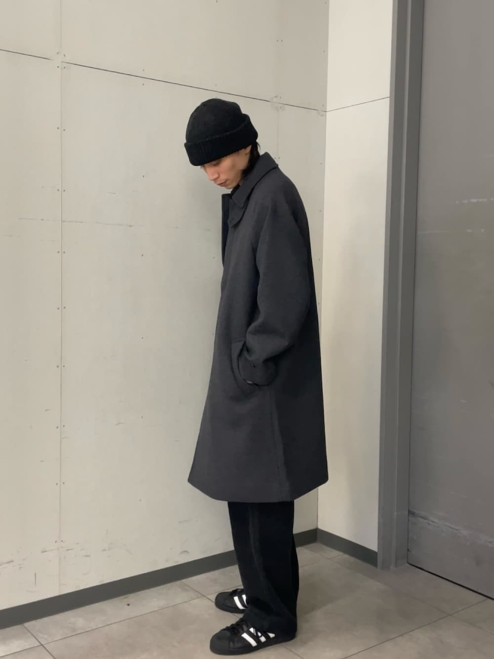 グレー系のステンカラーコート、ブラック系のニット/セーター、グレー系のその他パンツを着用したメンズの秋コーディネートの2枚目の写真