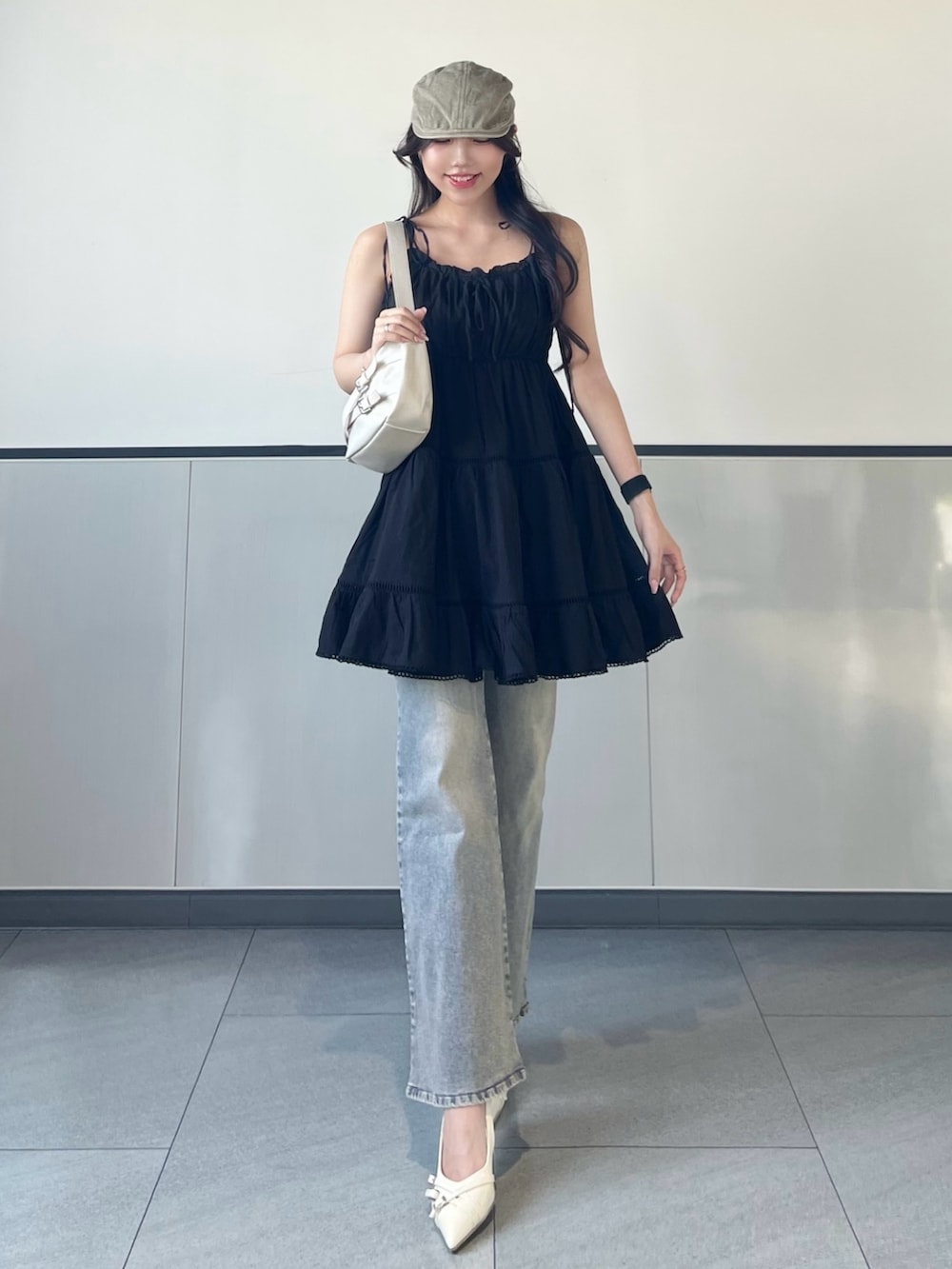 ブラック系のワンピース、ブルー系のデニムパンツ、ホワイト系のパンプスを着用したレディースの夏コーディネートの4枚目の写真