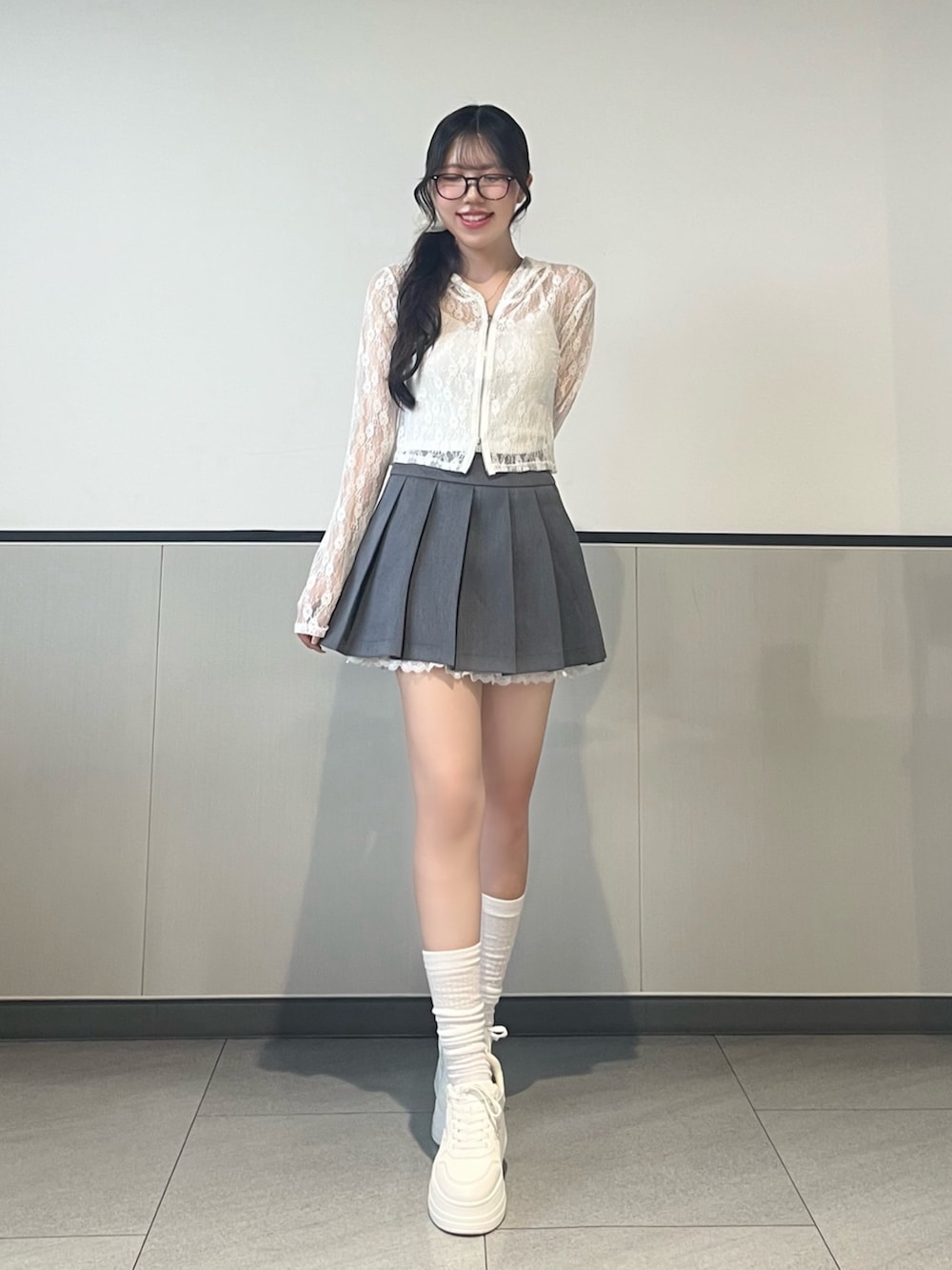 ホワイト系のパーカー、グレー系のスカート、ホワイト系のスニーカーを着用したレディースの夏コーディネートの3枚目の写真