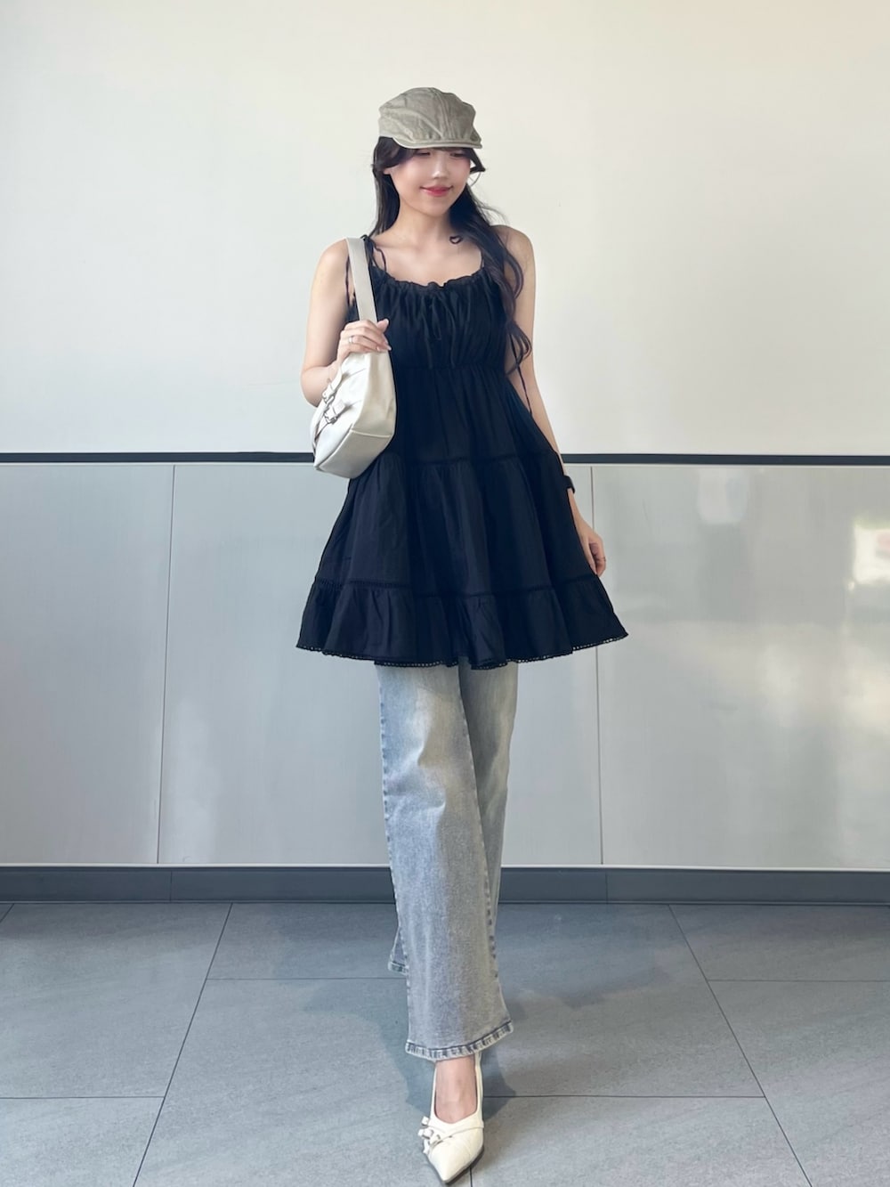 ブラック系のワンピース、ブルー系のデニムパンツ、ホワイト系のパンプスを着用したレディースの夏コーディネートの3枚目の写真