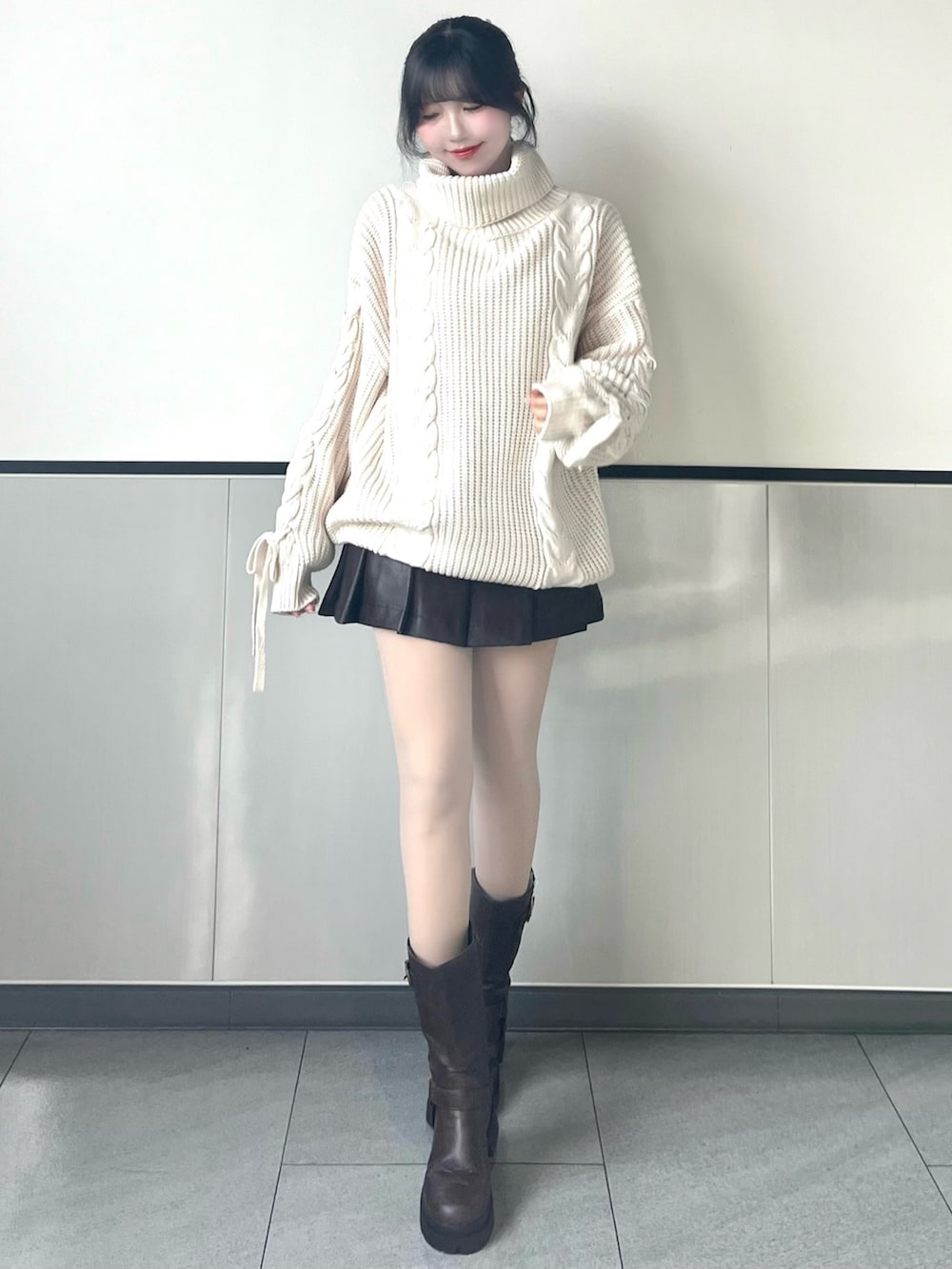 ホワイト系のチュニック、ブラウン系のスカート、ブラウン系のブーツを着用したレディースの冬コーディネートの2枚目の写真