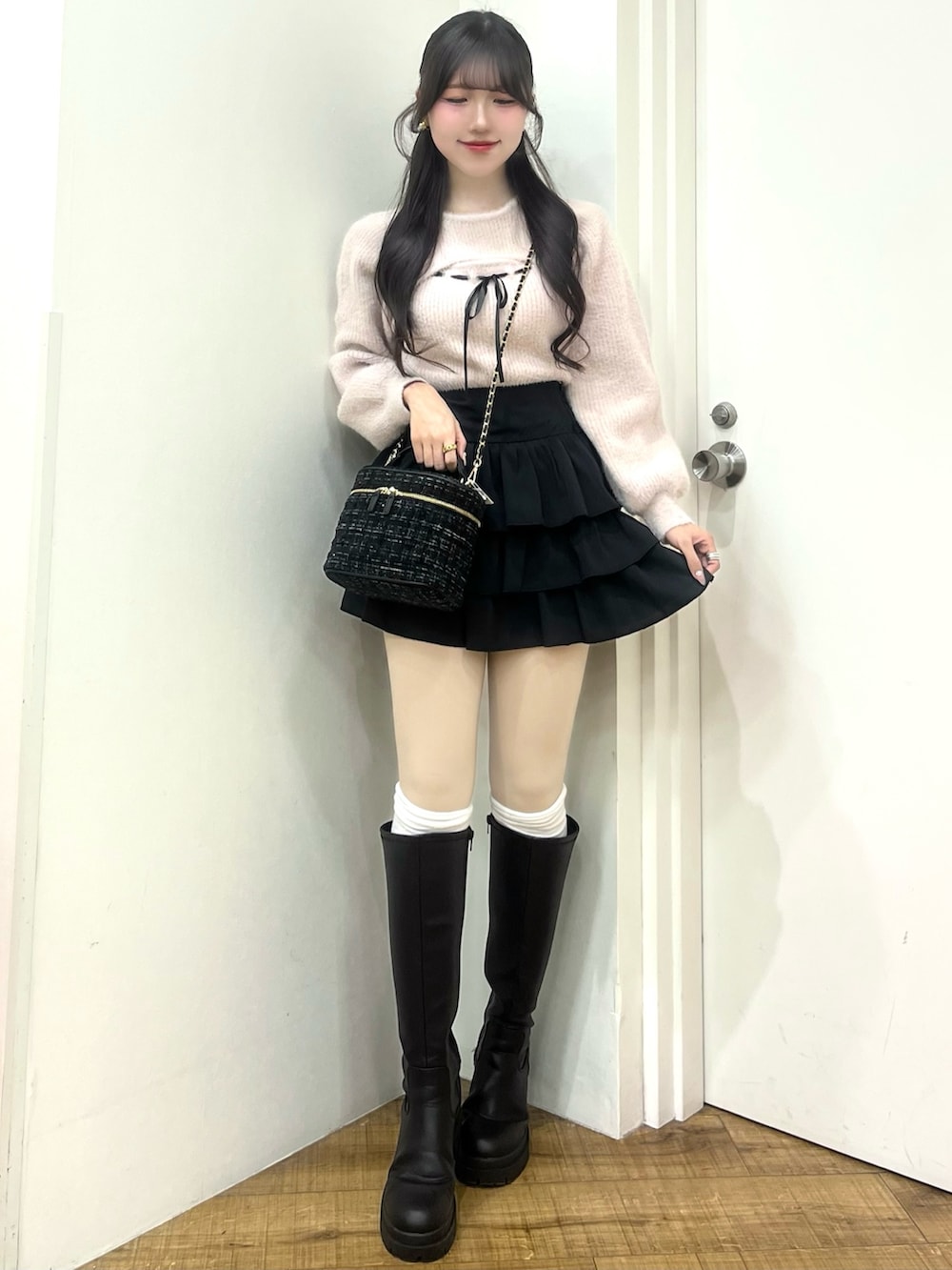 ピンク系のニット/セーター、ブラック系のスカート、ブラック系のショルダーバッグを着用したレディースの冬コーディネートの2枚目の写真